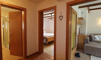 A bright and welcoming entrance hall with doors to various rooms. On the right side is a cozy living room and on the left side a bathroom.