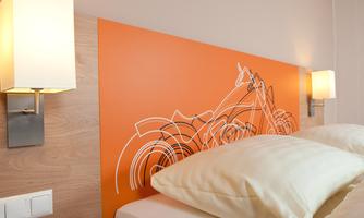 A modern bedroom with an orange headboard featuring a motorcycle design. Next to the bed, there are two stylish wall lamps.