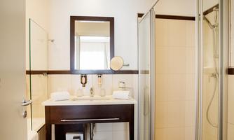 A modern bathroom with a shower and a sink. It features a large mirror surface and stylish furnishings.