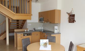 A modern kitchen corner with wooden shelves and a round dining area.  
Bright room with elegant furniture and an inviting atmosphere.