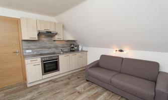 A modern kitchen with bright wooden cabinets and a cozy sofa. The room has an inviting and functional character.