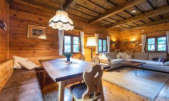 A cozy living space with wooden ceilings and walls. A dining table and a couch provide space to relax.