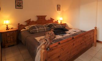 A cozy bedroom with a large wooden bed and two nightstands. Soft light from the lamps creates a relaxed atmosphere.