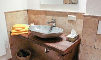 A modern bathroom with an elegant sink made of stone and wood. Towels in warm colors are neatly arranged.