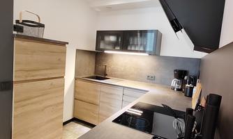 A modern kitchen with wood and concrete elements. It is well-lit and provides space for cooking utensils.