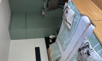 A modern bedroom with two beds and soft colors. There is a desk and a chair in the room.