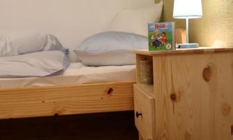A cozy bedroom with a bed and a night lamp. Next to the bed, there is a small table with a toy.
