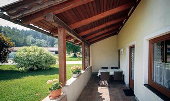 A cozy terrace with a table and chairs. In the background, you can see a green garden and trees.