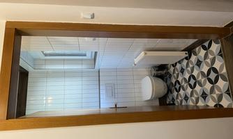 A small bathroom with a toilet and a radiator. The floor is decorated with pretty, patterned tiles.