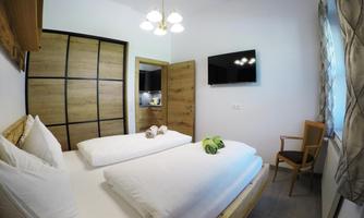 A bright room with two beds and modern furniture. A television hangs on the wall, and there is a comfortable chair.