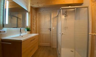 A modern bathroom with a shower and a wooden sink. The warm wooden details create a cozy atmosphere.