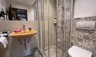 A modern bathroom with a shower and a sink. The walls are designed with decorative tiles.