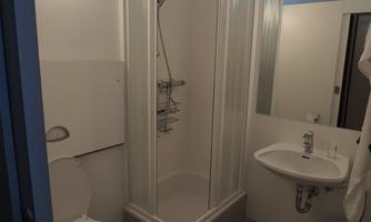 A small, clean bathroom with a shower, a toilet, and a sink. Bright walls and modern fixtures create a fresh atmosphere.