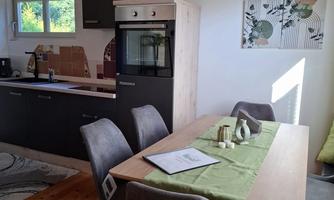 A modern kitchen with a dining area. The table is set with a green tablecloth and subtle decorations.