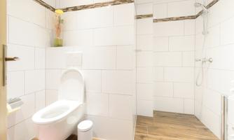 A modern bathroom with white tiles and a shower. The decor is simple and provides a pleasant atmosphere.