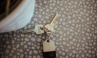 A keyring with three keys lies on a patterned table. One of the keys has a keychain.