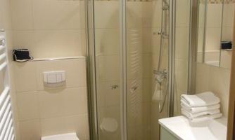 A modern bathroom with a shower cabin, a sink, and a toilet. Fresh towels are neatly placed on the sink.