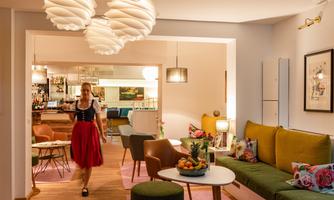 A stylish interior with comfortable seating and modern lighting. A woman in traditional clothing serves drinks in an inviting space.