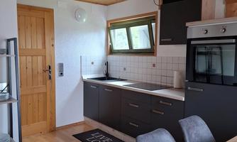 A modern kitchen with wooden ceilings and gray cabinets. There is a dining area with a table and chairs.