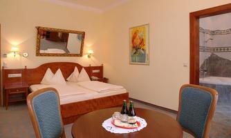A cozy room with a double bed and a table. On the table are drinks and small snacks, and there is a bathing area in the background.