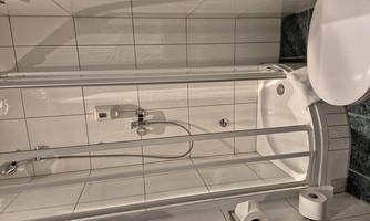 A small bathroom with a shower cubicle and a toilet. The walls are tiled and the design is bright and modern.