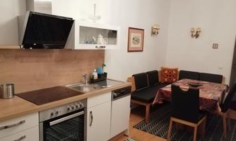 A cozy kitchen with modern appliances and a dining area. The table is set with a tablecloth and there are comfortable seats.