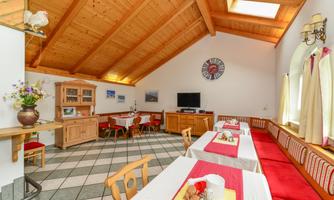 An inviting dining room with wooden ceilings and cozy seating areas. The tables are neatly set and decorated.