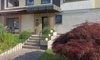 A beautiful house with a well-maintained garden. Colorful flowers and a covered terrace give the surroundings an inviting charm.