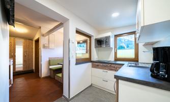 A modern kitchen with bright walls and large windows. It features an elegant countertop and a cozy dining area.