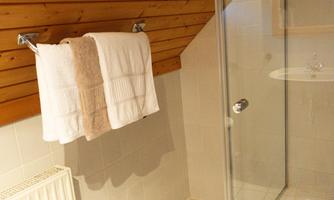 A modern bathroom with a shower and white towels. The wooden walls give the room a cozy atmosphere.