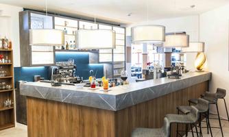 An elegant bar with a modern counter area. Various drinks are displayed on the counter, and the decor is stylish and inviting.