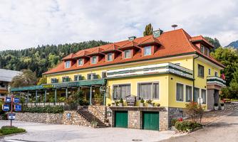 A cozy hotel with a yellow facade and a red roof. Surrounded by green nature and an inviting outdoor area.