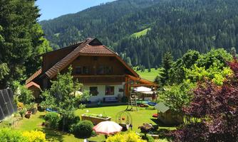 A beautiful house surrounded by green nature and mountains. The garden is inviting with play opportunities and colorful plants.