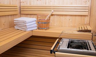 A cozy sauna with wooden paneling. Towels and a bucket with a sauna ladle are available.