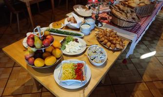 A hearty breakfast buffet with fresh fruits, cheese, vegetables, and assorted rolls. The tables are cozily set and invite you to linger.