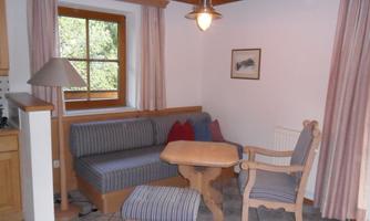 A cozy living area with a sofa and a table. The room has large windows and warm wood design.