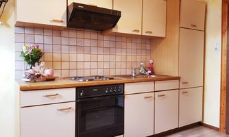 A modern kitchen with bright cabinets and a stove. On the countertop, there is a vase of flowers and there is a pleasant, inviting atmosphere.