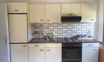 A modern kitchen with bright cabinets and a stove. The walls are decorated with vintage-style tiles.