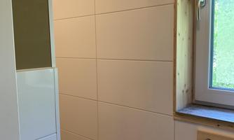 A modern shower room with white tiles and a window. The walls are designed to be bright and welcoming.