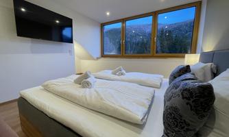 A cozy bedroom with two beds and fresh towels. Large windows offer a nice view of nature.
