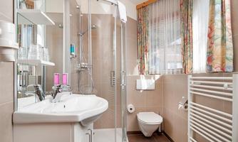 A modern bathroom with a shower cabin, sink, and toilet. The colorful curtains create a friendly atmosphere.