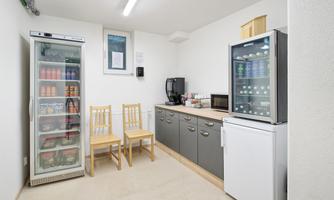 A tidy break room with two chairs, refrigerators, and a microwave. The room is bright and offers space for small snacks and drinks.