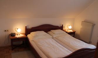 A cozy bedroom with a double bed and two nightstands. The room is bright and has a pleasant atmosphere.