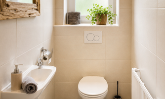 A modern bathroom with bright tiles and a large window. 

On the floor, there is a carpet with heart patterns.
