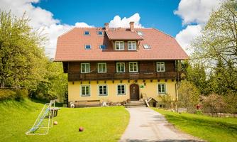 A charming three-story house with a red roof and yellow facade. The garden is green and inviting, ideal for recreational activities.