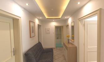 A modern hallway with white walls and ceiling lighting. On the left is a sofa and on the right is a narrow cabinet with a mirror.