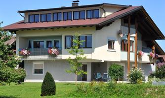A modern house with a large garden and colorful flowers. The facade is bright and well-maintained, ideal for families.