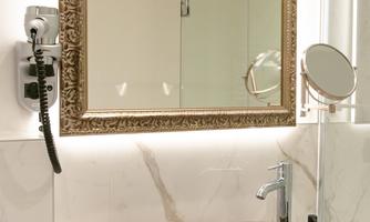 A modern bathroom with an elegant stone sink. In the background, there is a large mirror with a decorative frame.