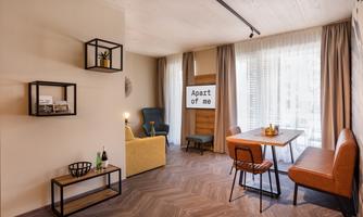 A modern living environment with a cozy sofa and a dining table. Large windows provide plenty of daylight and a friendly atmosphere.