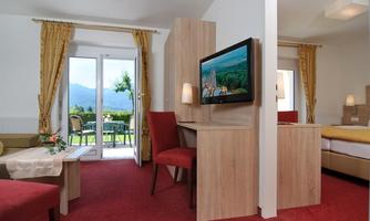 A cozy room with a red carpet and modern furniture. There is a balcony with a view of the mountains.
